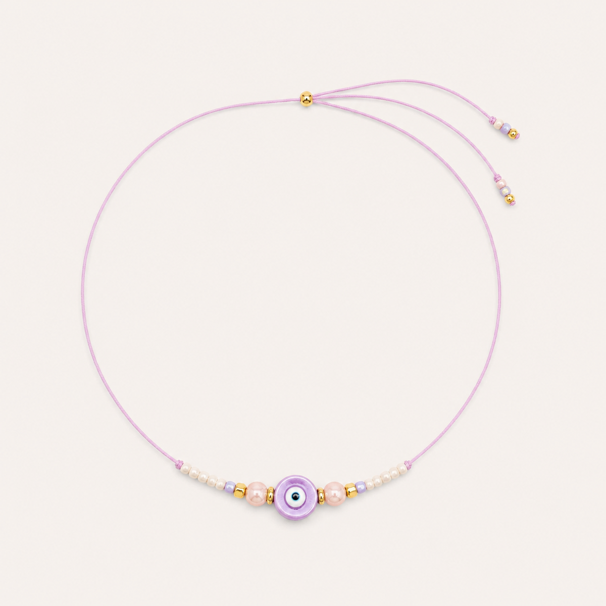 Purple cord Big Eye NECKLACE with beaded pearl and glass accents around a lilac enamel evil eye charm, laid flat.