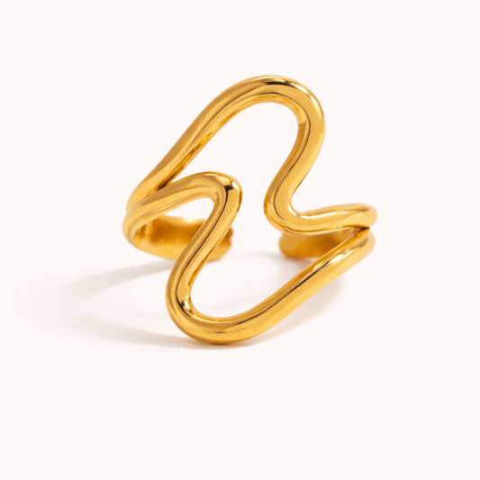 Gold ring formed from wavy interlocking loops in an abstract wave shape, shown on a cream backdrop — Folie à Trois Big Wave RING.
