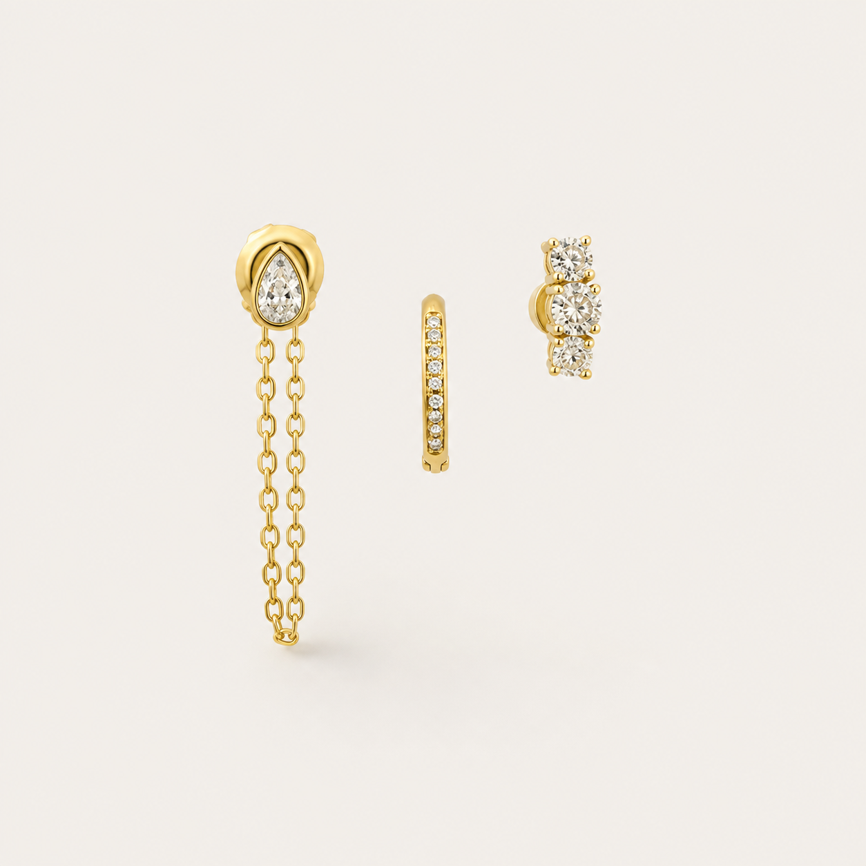 Gold earring set with a pear-cut zirconia chain-drop stud, a pavé huggie hoop, and a three-stone climber stud — Folie à Trois Bijou SET.