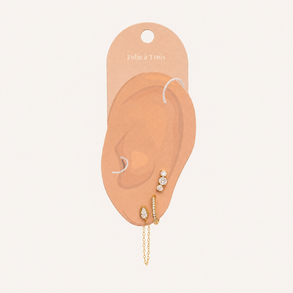 Folie à Trois Bijou SET displayed on a branded ear-shaped card, showing the stud, pavé hoop and chain-drop placement.