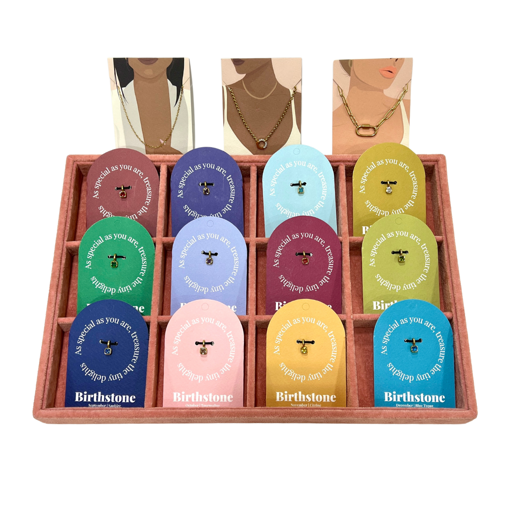 The Birthstone Charm BUNDLE in a black tray of twelve Birthstone gift tags, shown from an angled perspective with lifestyle cards above.