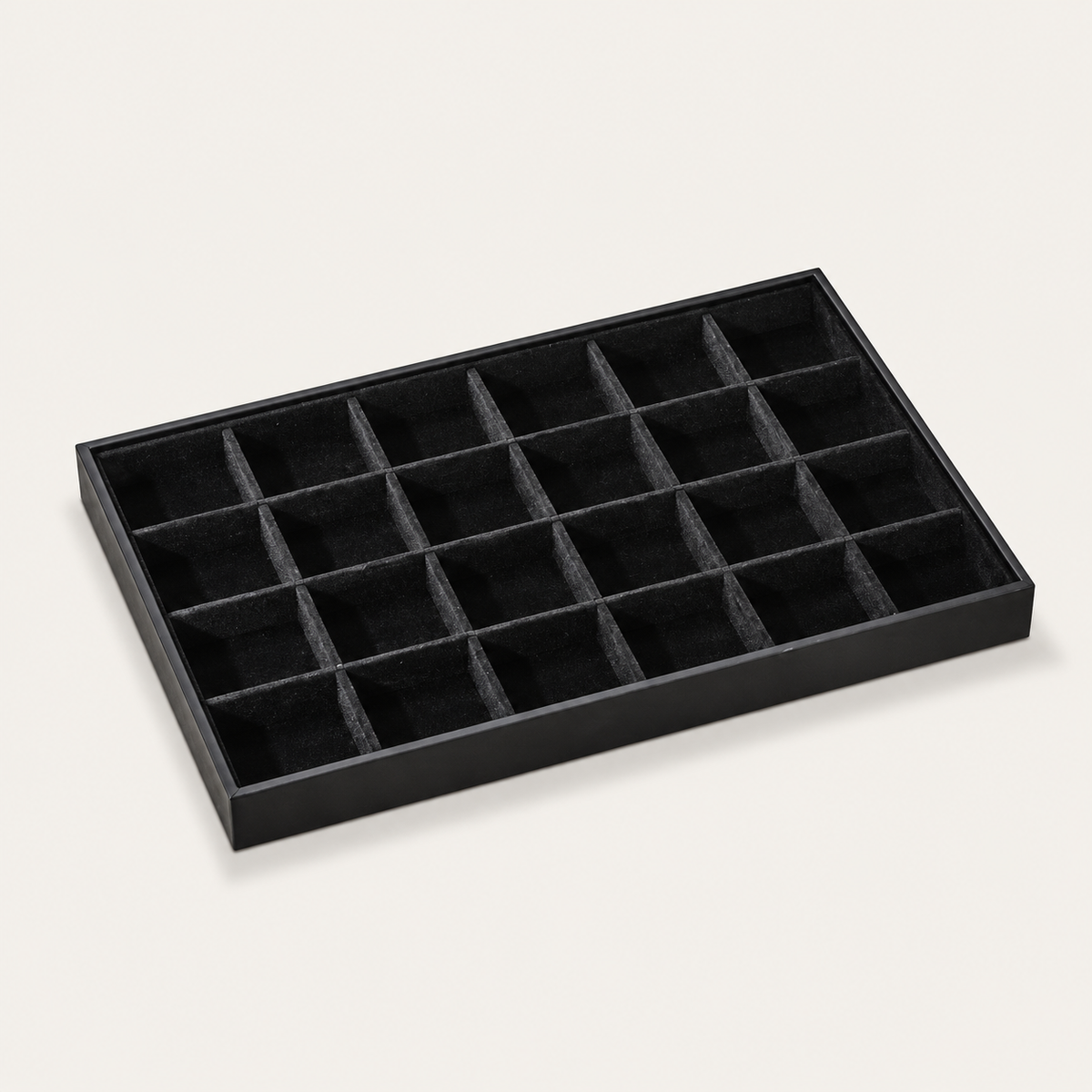 Black jewelry tray display lined with small square velvet compartments for organizing stud earrings and rings.