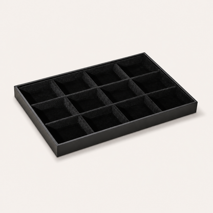 Black jewelry tray display lined with larger square velvet compartments for organizing rings and jewelry sets.