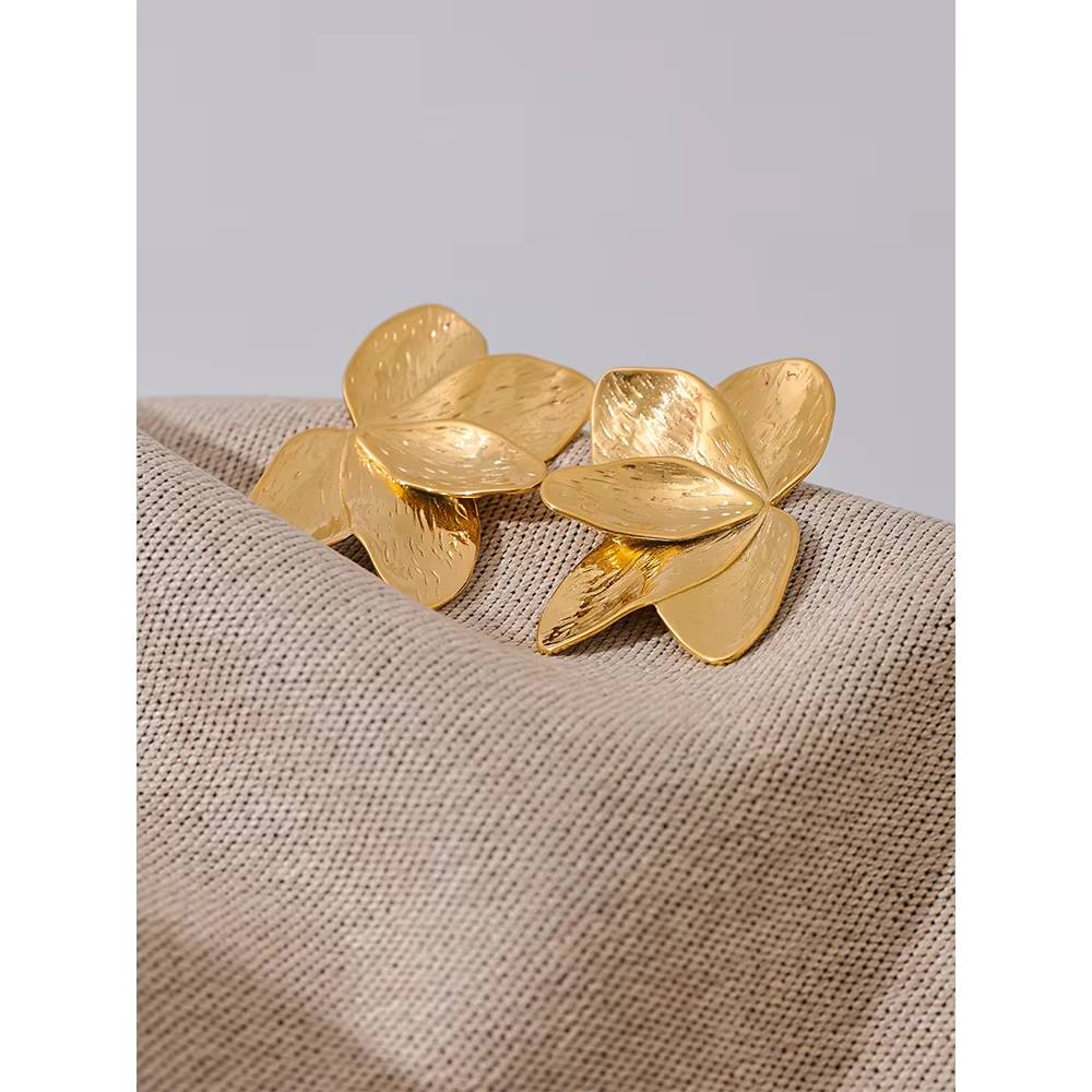 Bloom Earrings in gold styled on soft woven fabric, showing the layered textured petal shape up close.