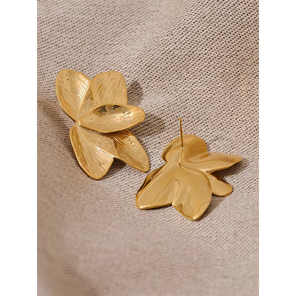Close-up of Bloom Earrings in gold resting on woven fabric, highlighting the brushed petal texture nicely.