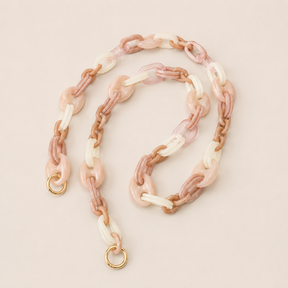 Folie à Trois Bracken long wholesale phone chain in pink, tan and white marbled acetate links with gold clasps, coiled on a cream background.