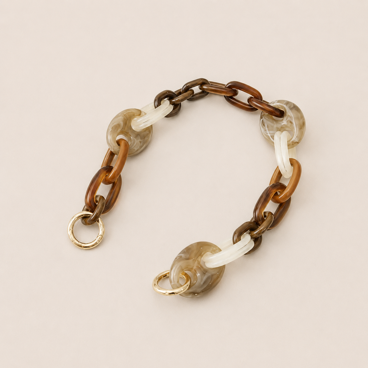 Folie à Trois Bracken short wholesale phone chain in brown, tan, white and gray marbled acetate links with gold clasps, laid flat on a cream background.