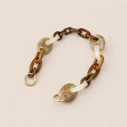 Folie à Trois Bracken short wholesale phone chain in brown, tan, white and gray marbled acetate links with gold clasps, laid flat on a cream background.