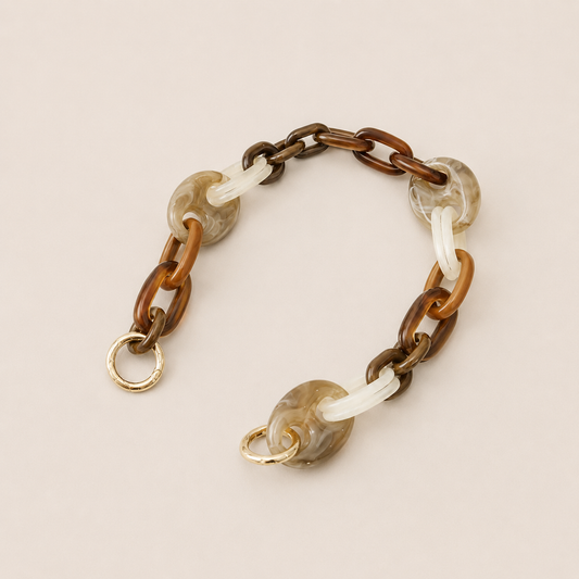 Folie à Trois Bracken short wholesale phone chain in brown, tan, white and gray marbled acetate links with gold clasps, laid flat on a cream background.