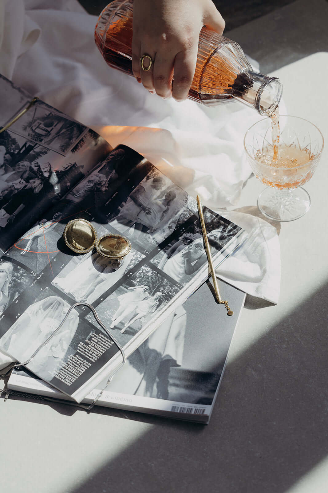 Braided Babe BRACELET styled lifestyle shot of gold cufflinks and a pouring rose drink on a vintage magazine.