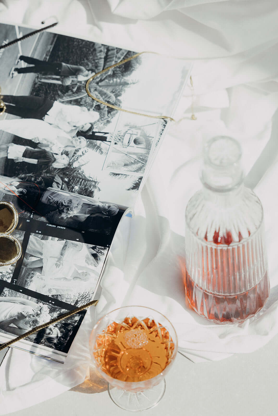 Braided Babe BRACELET styled lifestyle shot of a vintage magazine, gold trinkets and a glass of rose on white linen.