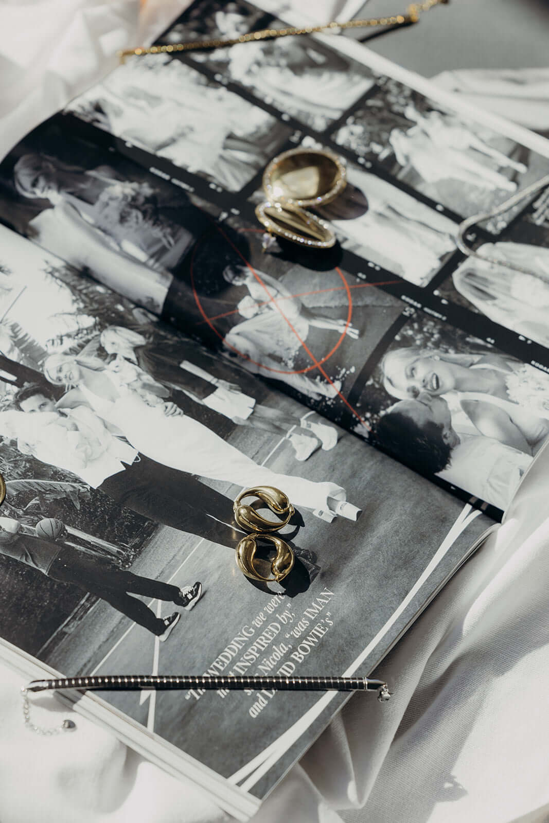 Braided Babe BRACELET styled lifestyle shot with gold knot rings and a beaded bracelet on an open magazine.