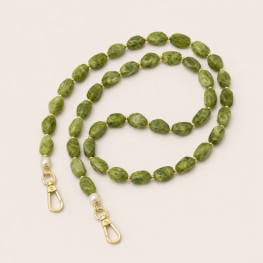 Folie à Trois Briar long wholesale phone chain in green marbled nugget beads with gold spacers, pearl accents and gold clasps, coiled on a cream background.