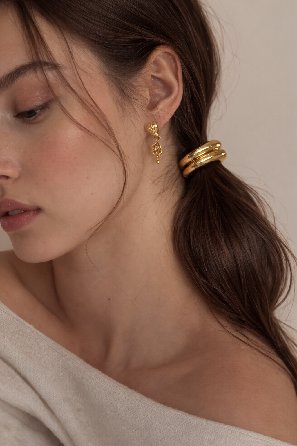 Bridgette Hair Tie worn on a low ponytail, close-up of the ridged gold bead with drop earrings.