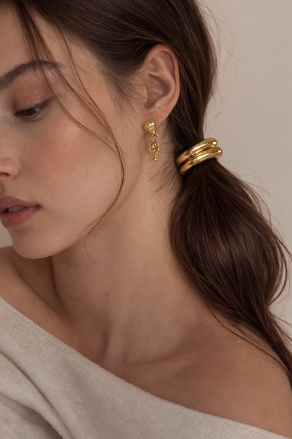 Bridgette Hair Tie worn on a low ponytail, close-up of the ridged gold bead with drop earrings.