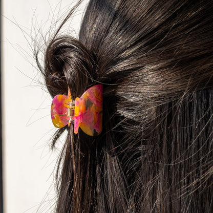 Bubblegum HAIR CLIP in pink and orange, worn holding a twisted bun on dark hair, close-up side view.
