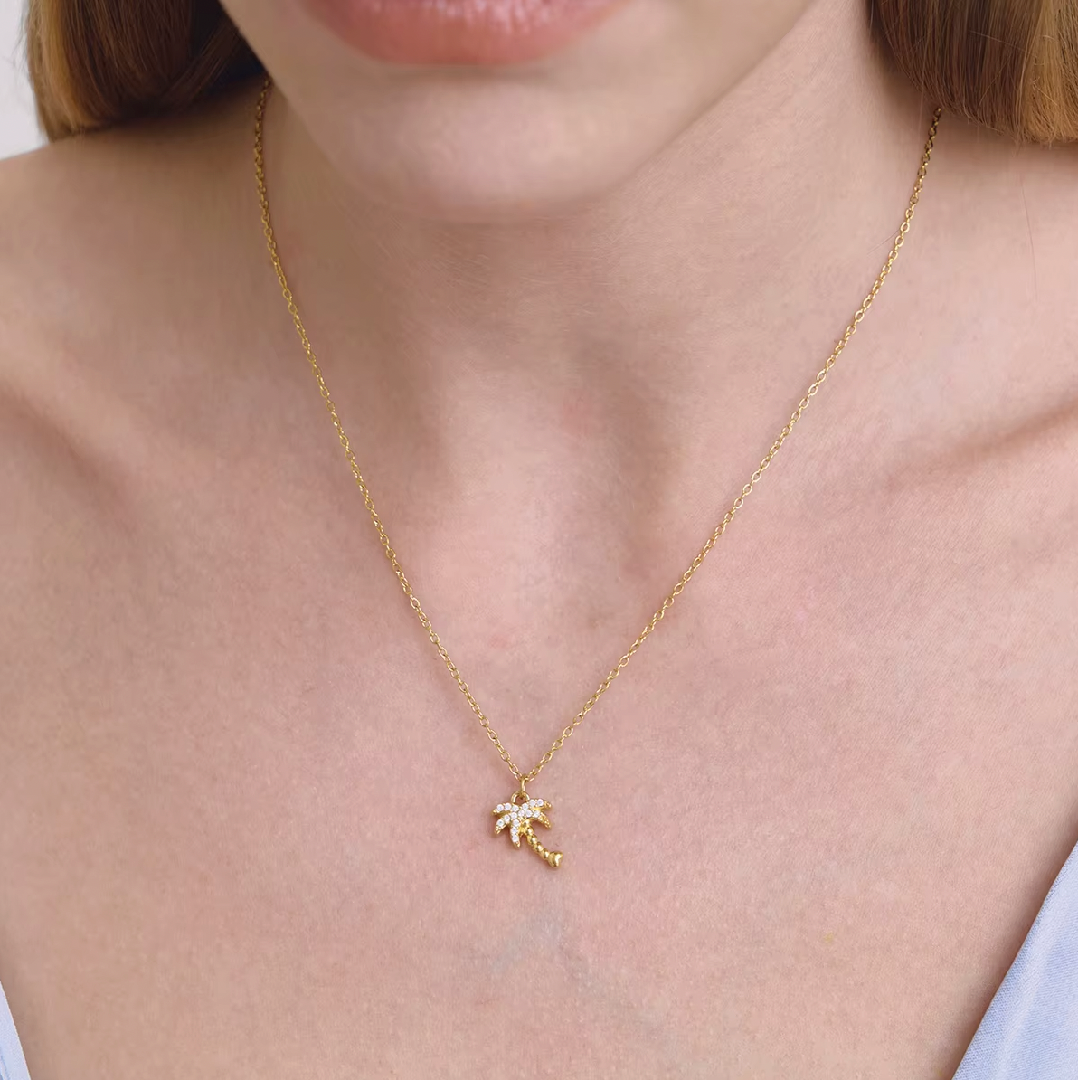 The By The Sea NECKLACE in the pave palm tree style, worn close-up at the neckline on a fine gold chain.