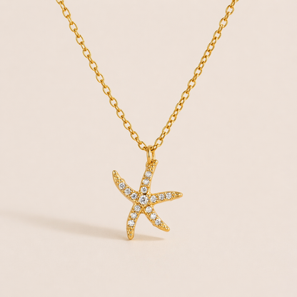 The By The Sea NECKLACE in the pave starfish style, hanging against a plain beige background to show its crystal-set points.