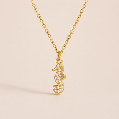 The By The Sea NECKLACE in the pave seahorse style, hanging against a plain beige background to show its crystal detailing.