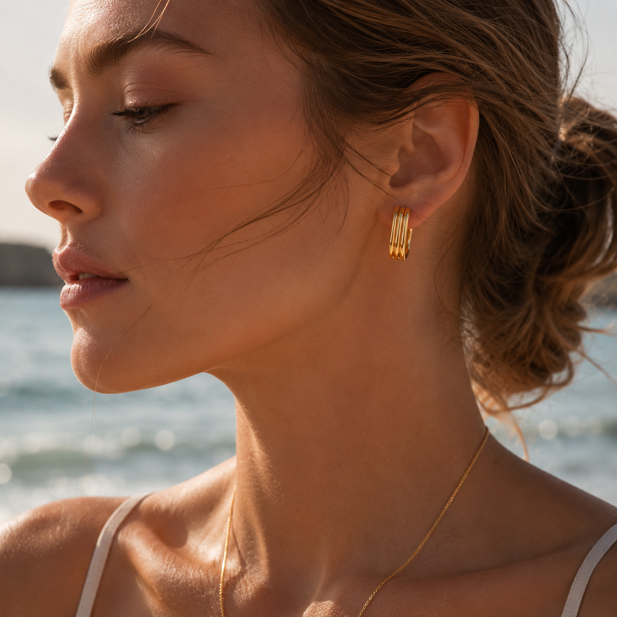 A model wears a gold Cami EARRINGS hoop with multiple stacked ridged bands in a rounded rectangular silhouette.