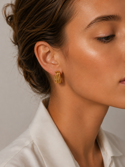 Close-up of a model wearing a gold Cami EARRINGS hoop with multiple stacked ridged bands on her ear.