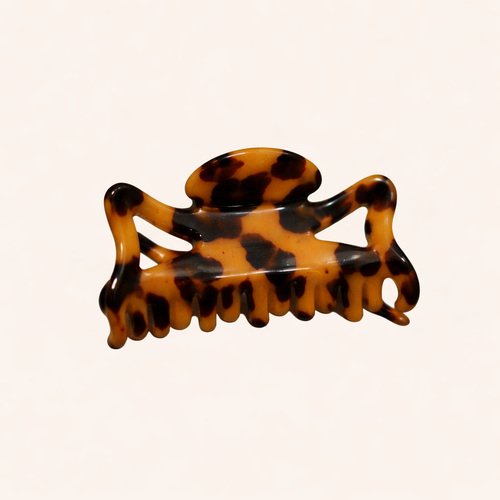 Amber and black tortoiseshell rectangular acetate claw clip from the Capri HAIR CLIP collection, shown on a cream studio background.