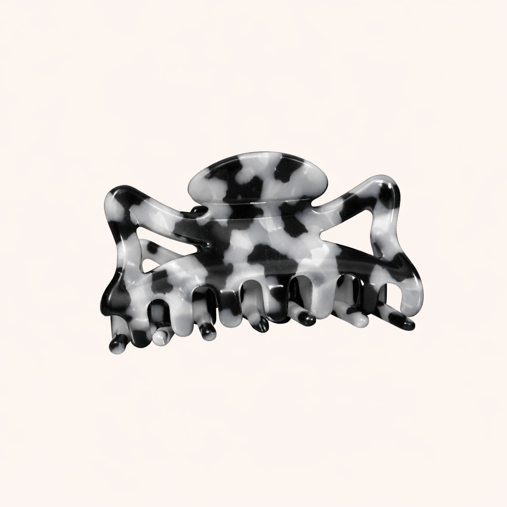 Black and white marbled acetate claw clip from the Capri HAIR CLIP collection, shown on a cream studio background.