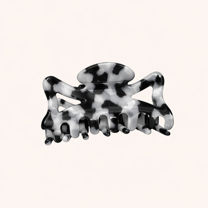 Black and white marbled acetate claw clip from the Capri HAIR CLIP collection, shown on a cream studio background.