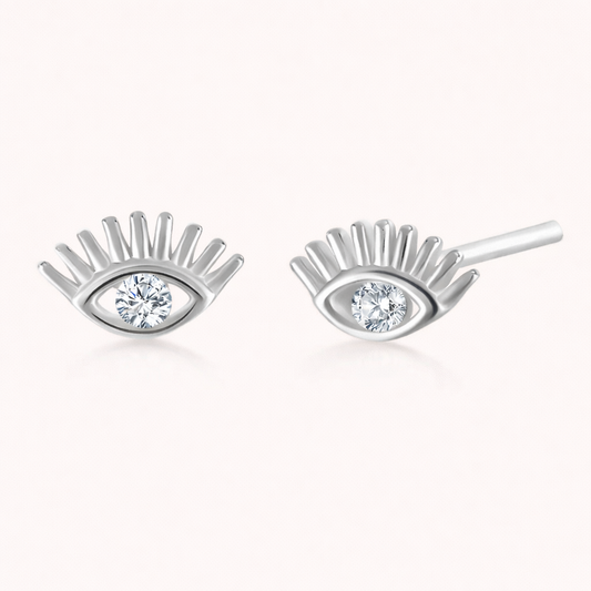 Captured In Your Eyes Earrings shape a silver evil-eye stud with lash-like rays and a sparkling clear center stone.