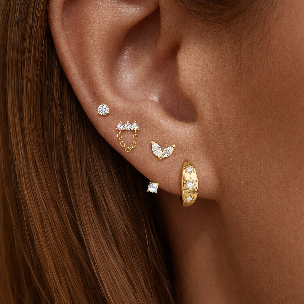 Capucine Set worn on the ear, gold studs, a leaf-shaped drop, a chain stud, and a starry pave hoop stacked together.