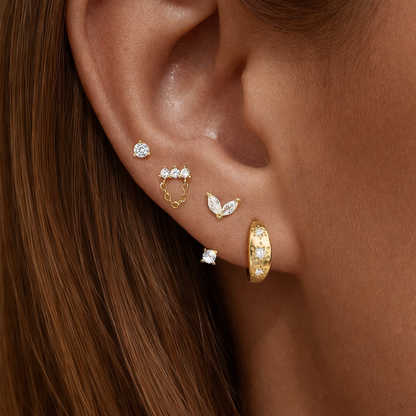Capucine Set worn on the ear, gold studs, a leaf-shaped drop, a chain stud, and a starry pave hoop stacked together.