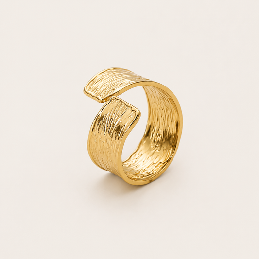 Gold open ring with a wavy, hammered-texture wraparound band, shown in close-up on a cream backdrop — Folie à Trois Cassis RING.