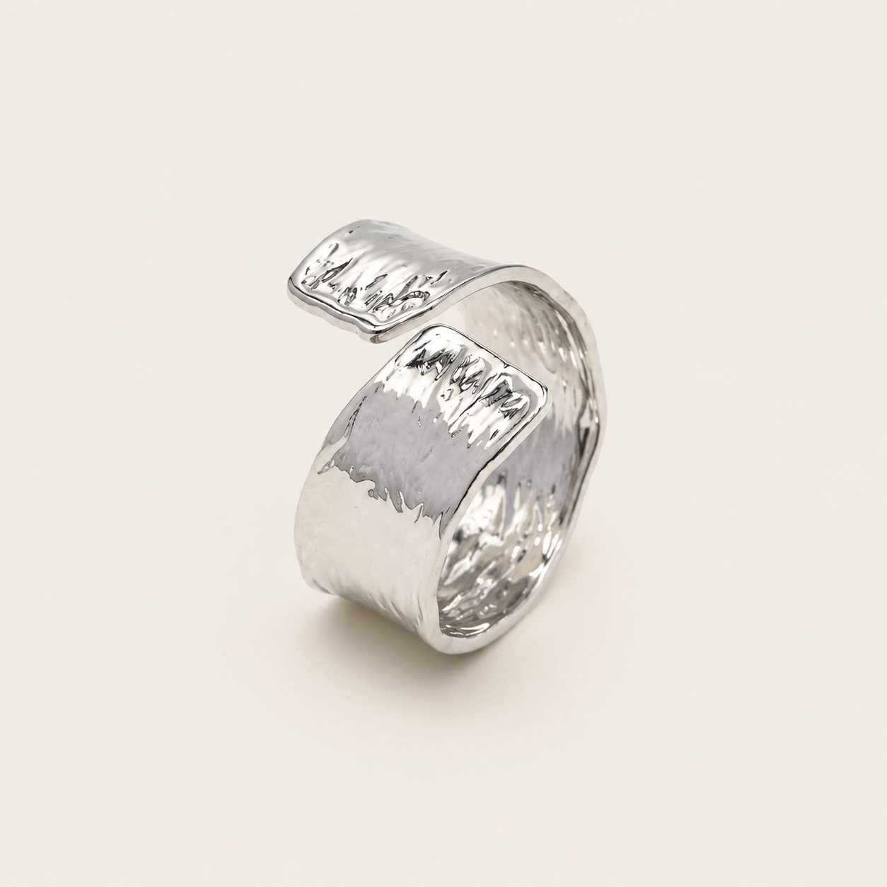 Silver open ring with a wavy, hammered-texture wraparound band, shown in close-up on a cream backdrop — Folie à Trois Cassis RING.