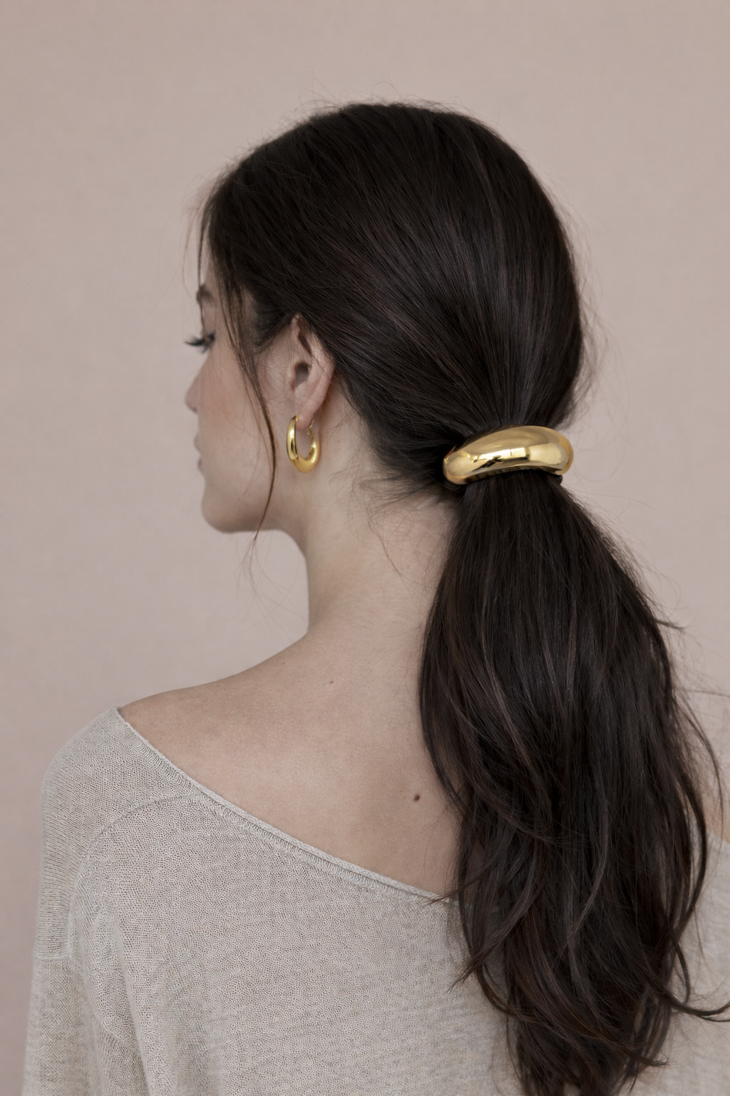 Cecil Hair Tie worn on a low ponytail, gold bead accent on dark hair, model in a beige sweater.