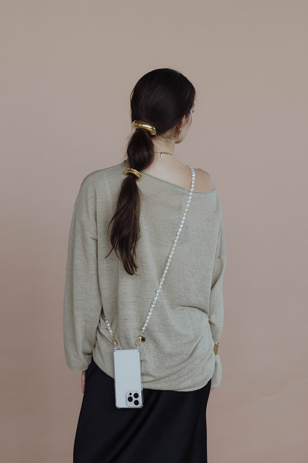 Cecil Hair Tie worn stacked on a low ponytail, model carrying a pearl phone strap and black skirt.