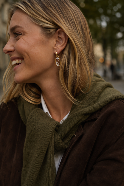 Model wears the gold Folie à Trois Celia EARRINGS, a teardrop link drop set with zirconia stones, styled outdoors with a scarf.