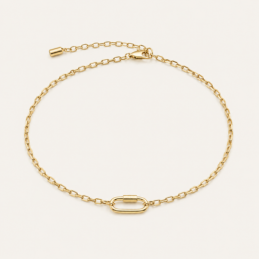 Chain link Charm BRACELET in gold with a paperclip chain and an oval carabiner-style clasp, shown flat on beige.