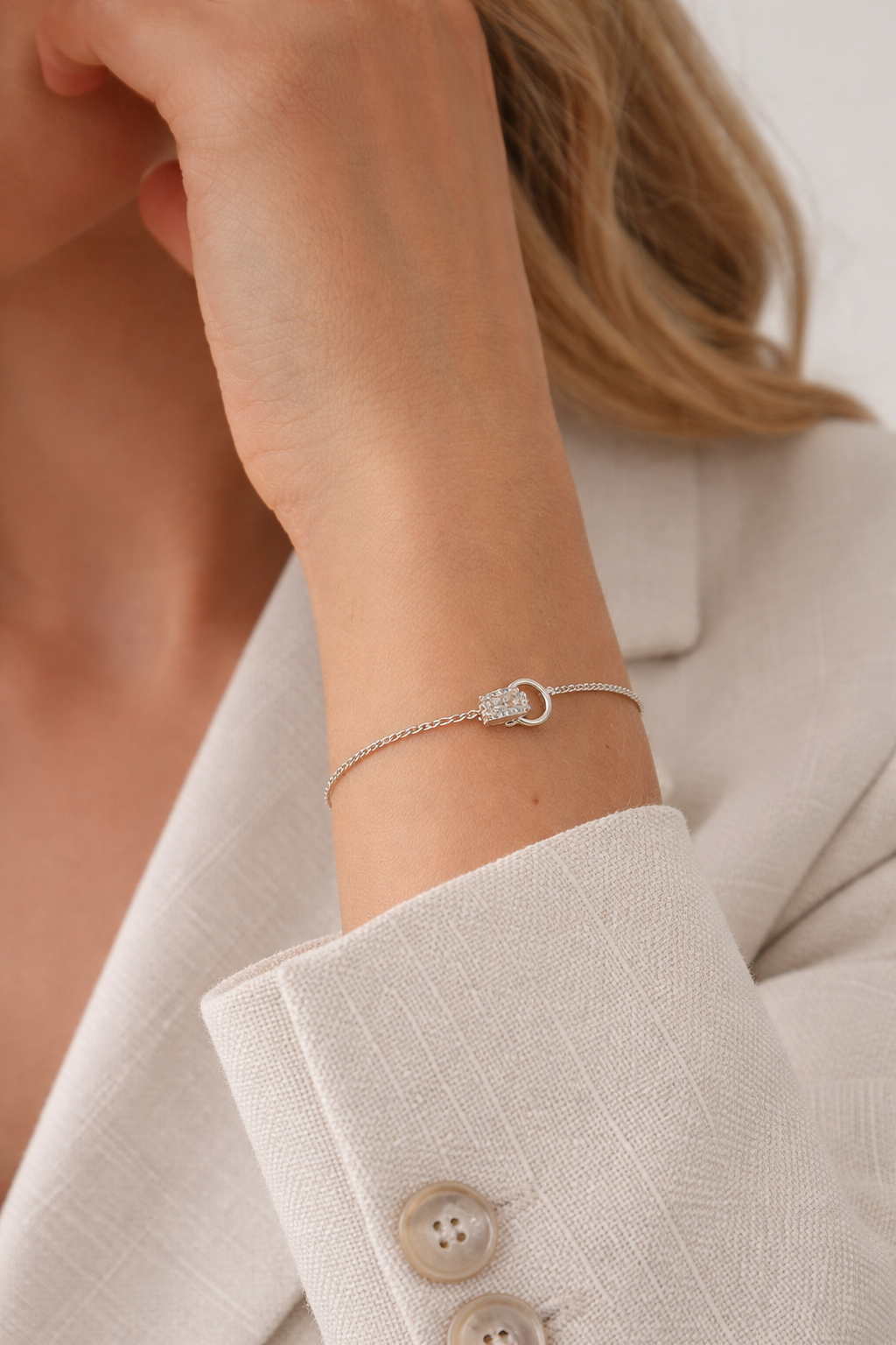 Chasing Highs BRACELET worn on the wrist, close-up of the pave crystal ring charm with a beige blazer sleeve.