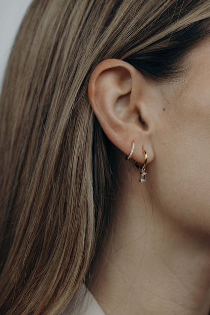 Classic Drop Earrings worn on the ear, the smooth gold hoop with a small baguette crystal drop catching light.