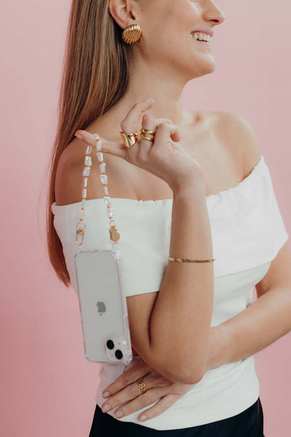 Clear Classic iPHONE CASE with a white pearl beaded strap draped over a model's shoulder, pink background.