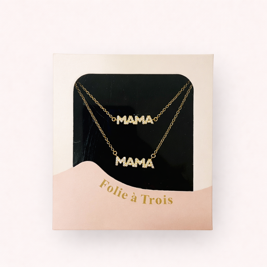 Clear-top pink gift box from Folie à Trois displaying a double MAMA pavé necklace set on a black velvet card.