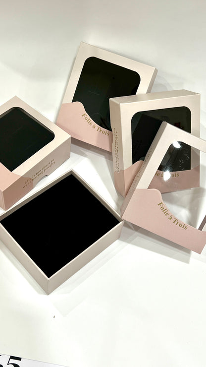 Overhead view of scattered clear gift boxes with one open box revealing its black velvet interior.