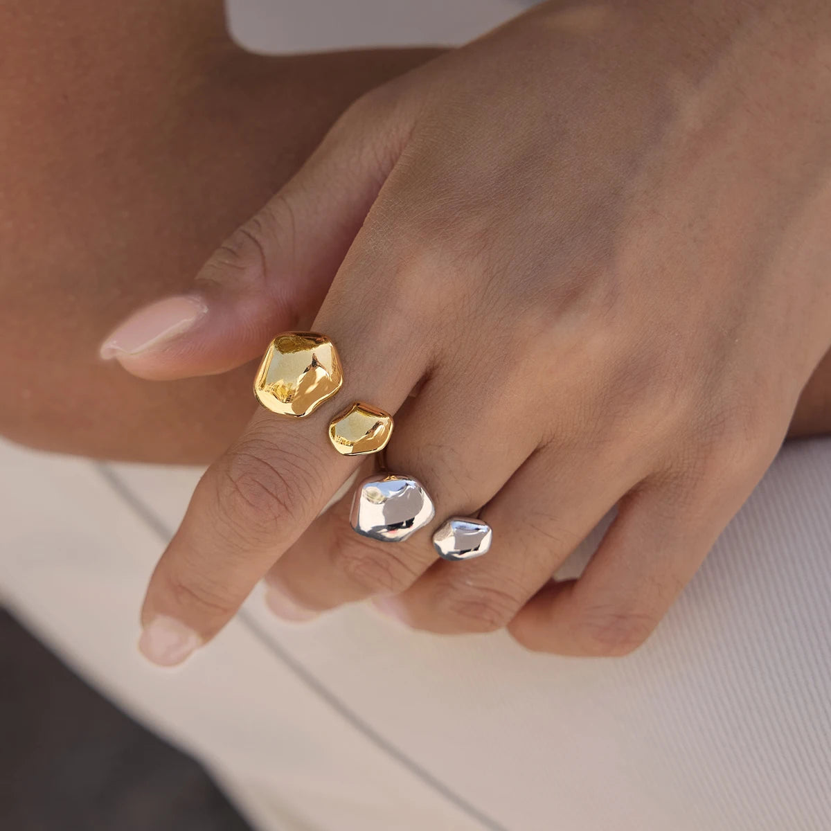Hand wearing gold and silver-tone Cloud RINGS with organic pebble shapes, stacked on two fingers — Folie à Trois