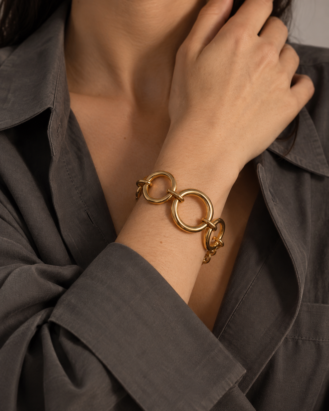 Close-up of a model's wrist wearing the gold Folie à Trois Cluster BRACELET, hand raised to her collarbone.