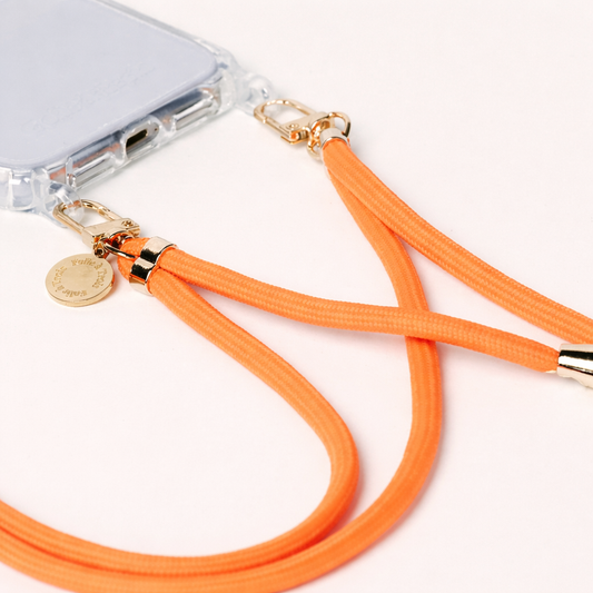 Orange Colorful PHONE CORD attached to a clear phone case, close-up on a light surface.