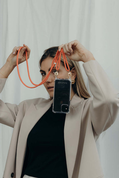 Orange Colorful PHONE CORD looped overhead as a model holds her clear phone case up to her face.