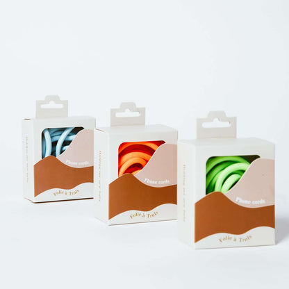 Three Colorful PHONE CORD packaging boxes showing light blue, orange and green cords by Folie à Trois.