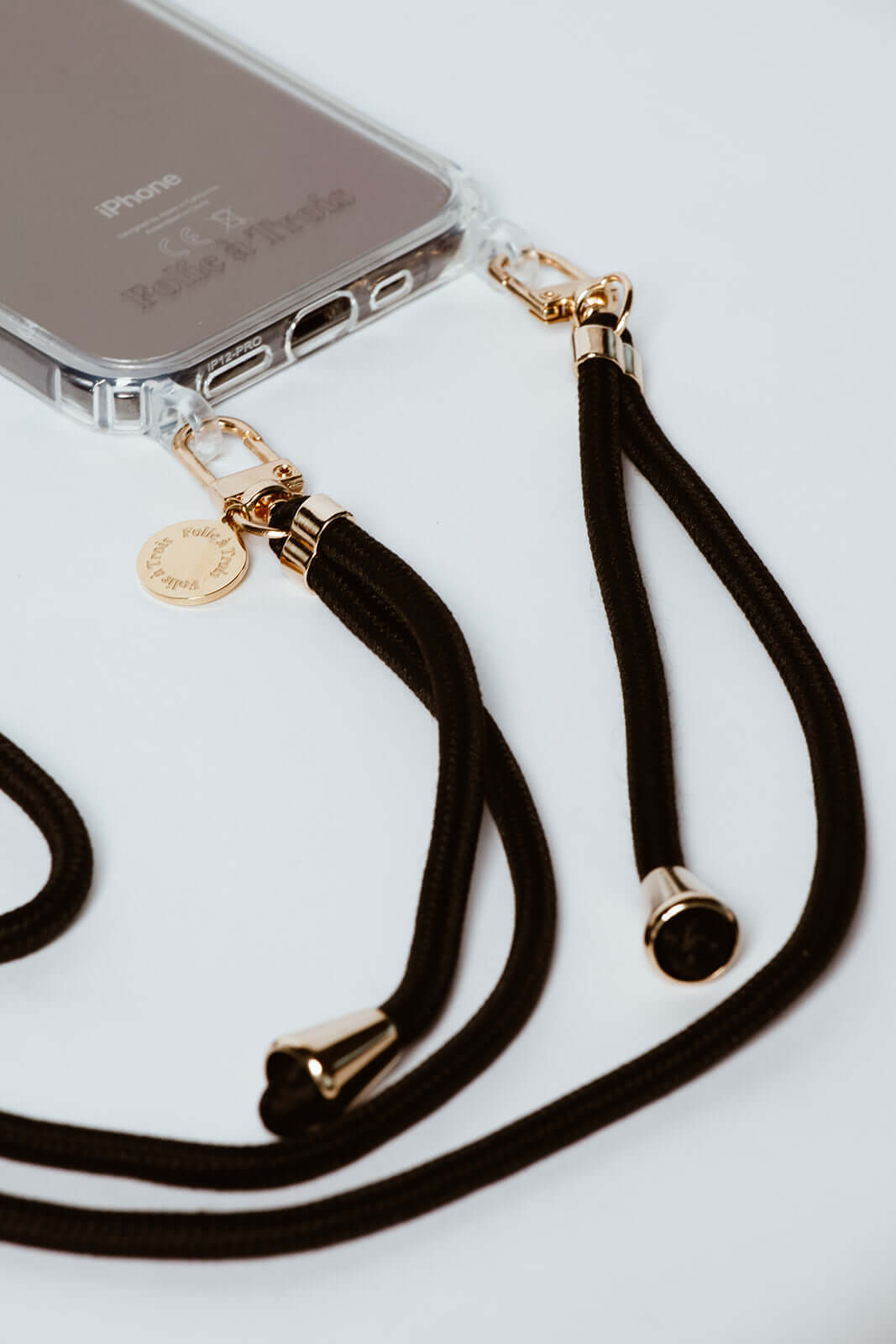 Close-up of black Colorful PHONE CORD gold-tone clasps attached to a clear iPhone case.