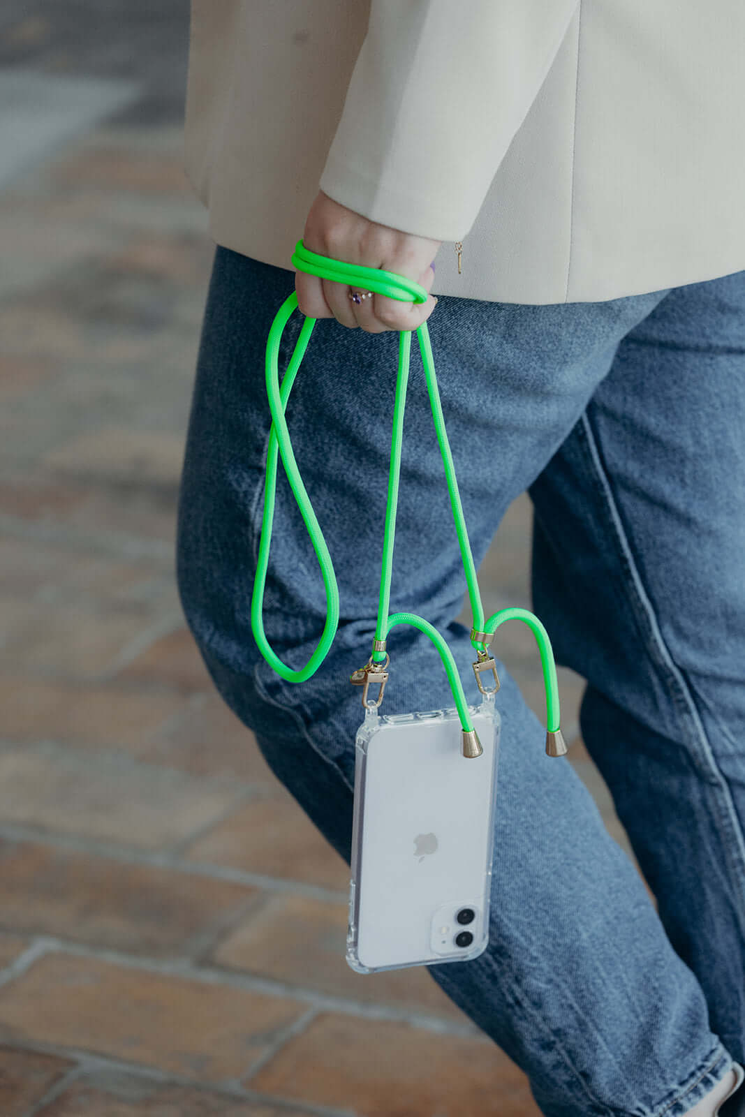 Neon green Colorful PHONE CORD, model walking outdoors with her phone in a clear case.