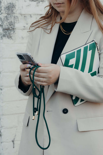 Dark green Colorful PHONE CORD, model holding her phone beside a green striped clutch bag.
